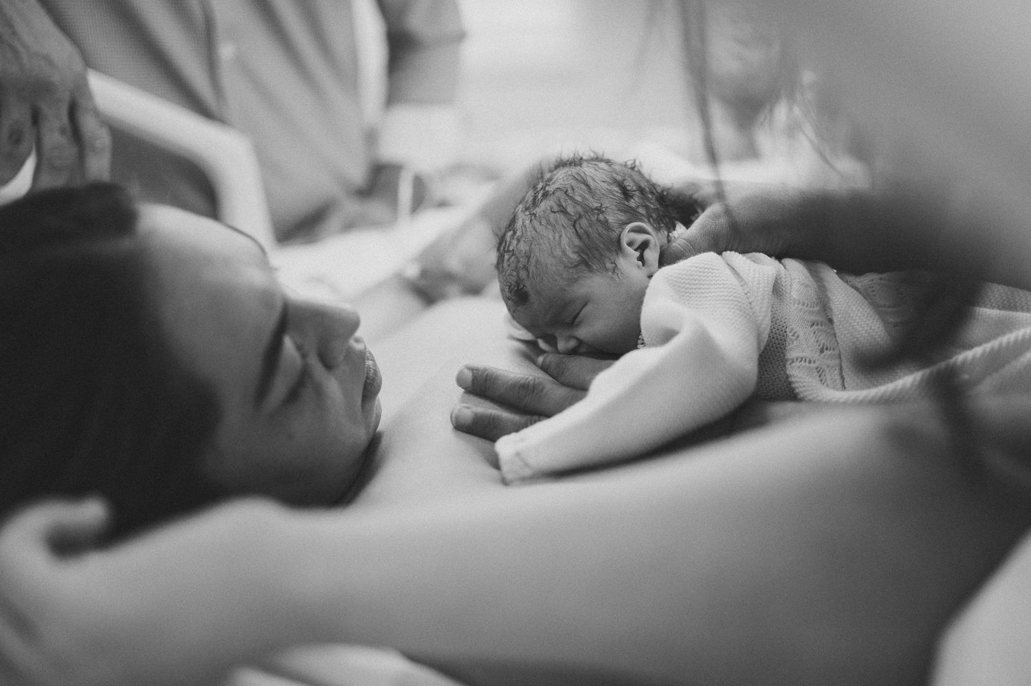 Black and white photograph capturing intimate moment during childbirth.