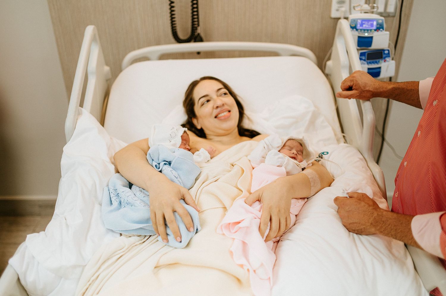 New mother resting in hospital bed with twin babies.