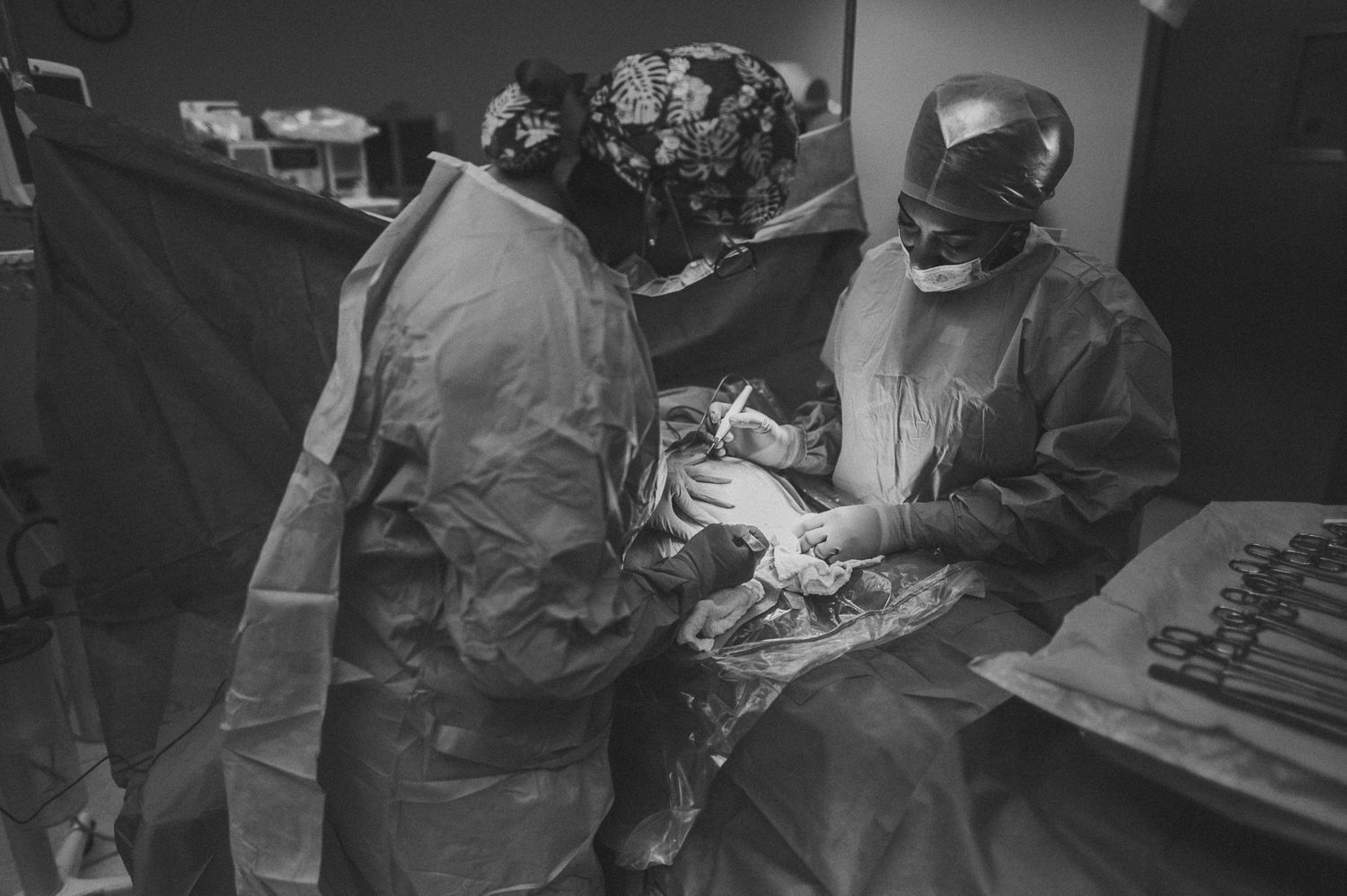 Surgeons in protective gear performing an operation with medical instruments.
