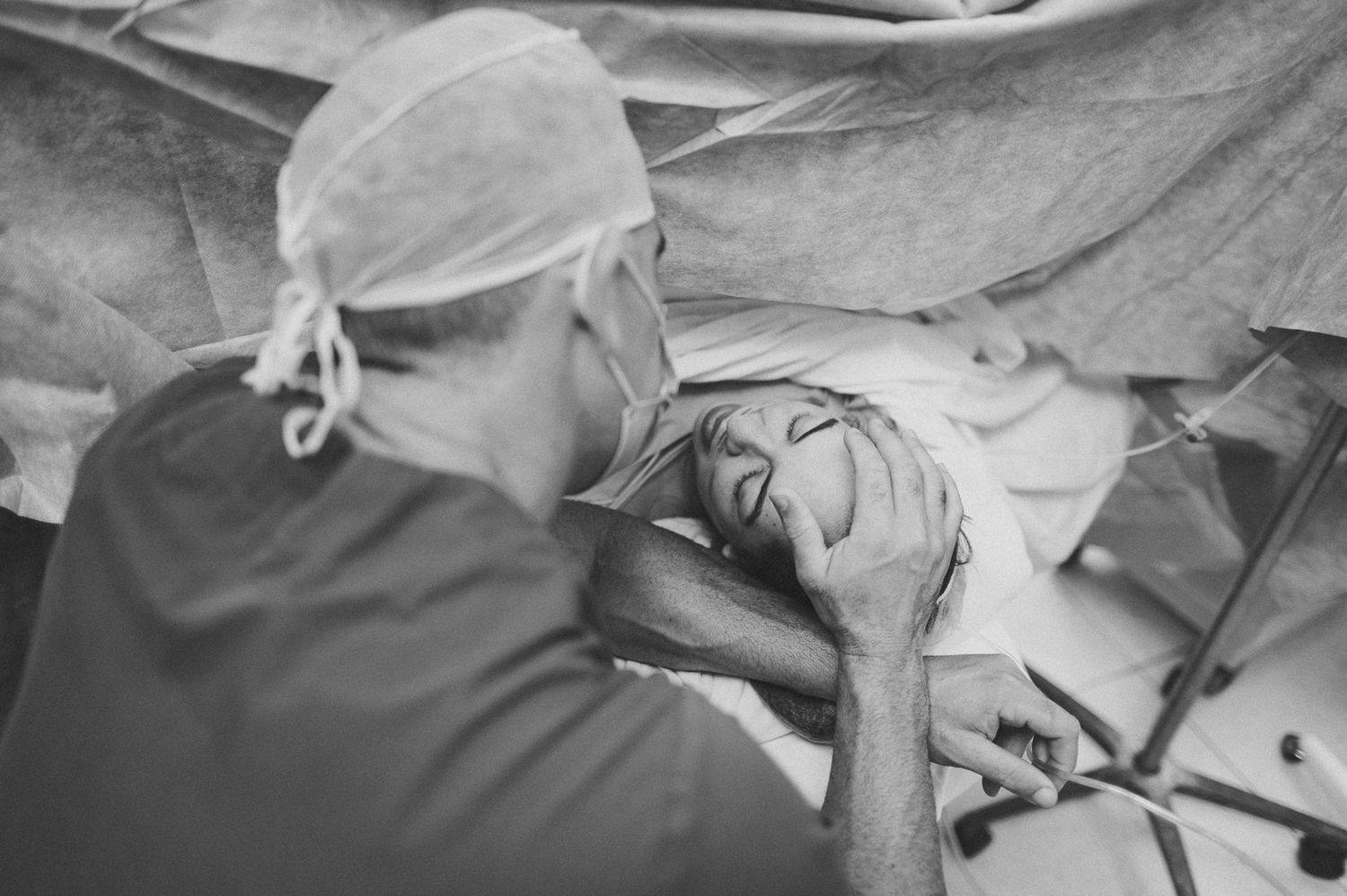 Healthcare provider wearing surgical cap tends to patient during medical procedure.