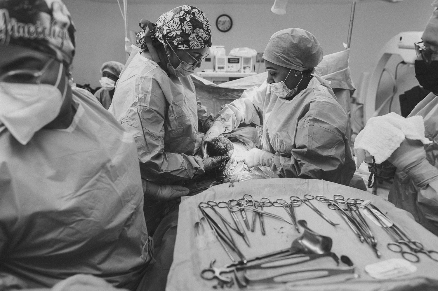 Medical team in surgical attire working together during an operation with instruments visible.