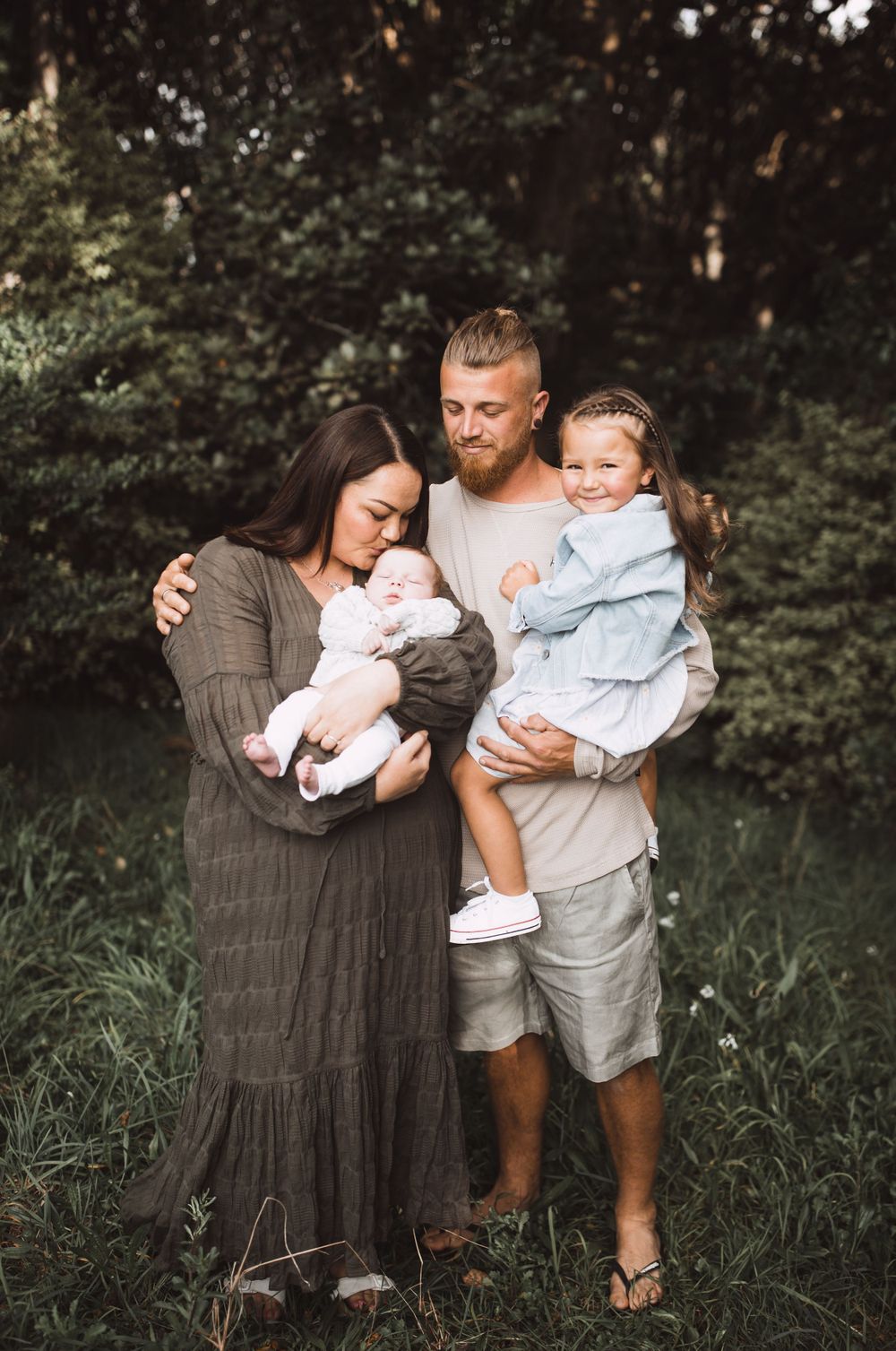 Family photo session in lush garden setting with casual summer outfits.