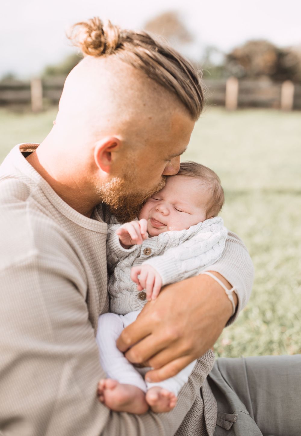 Tender moments between parent and baby during outdoor photo session.