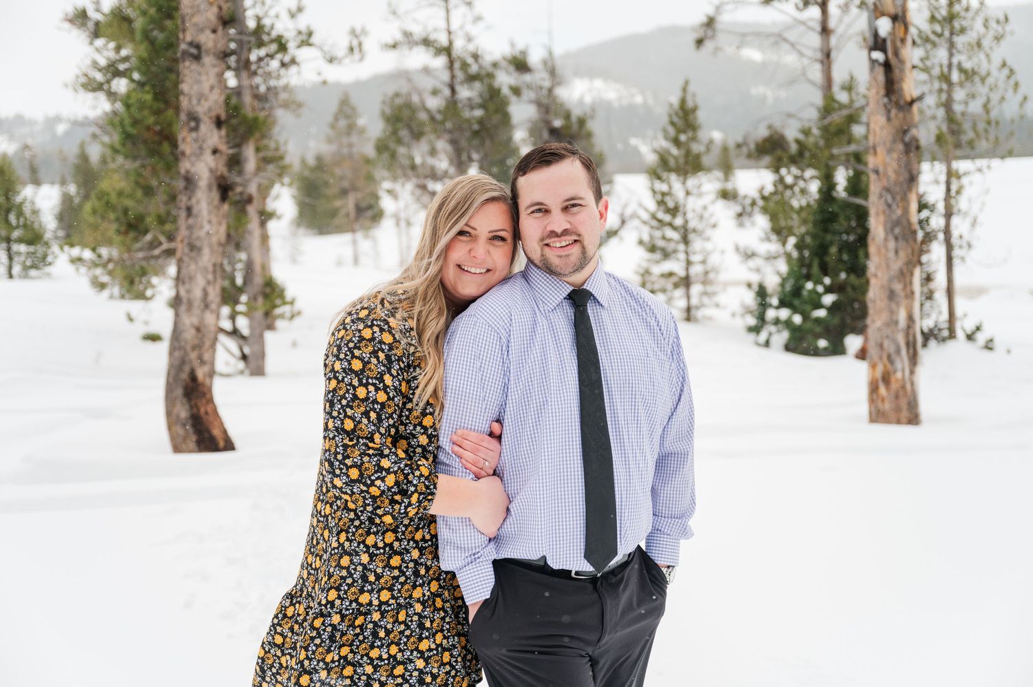 A happy couple smiling together in a snowy mountain setting.