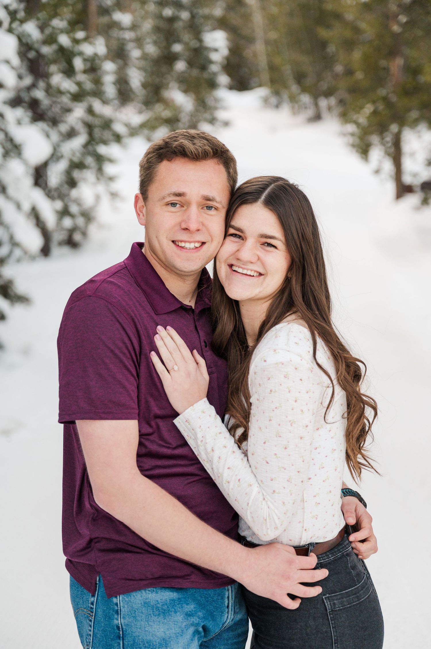 A couple embracing while posing for a portrait in a snowy mountain landscape.