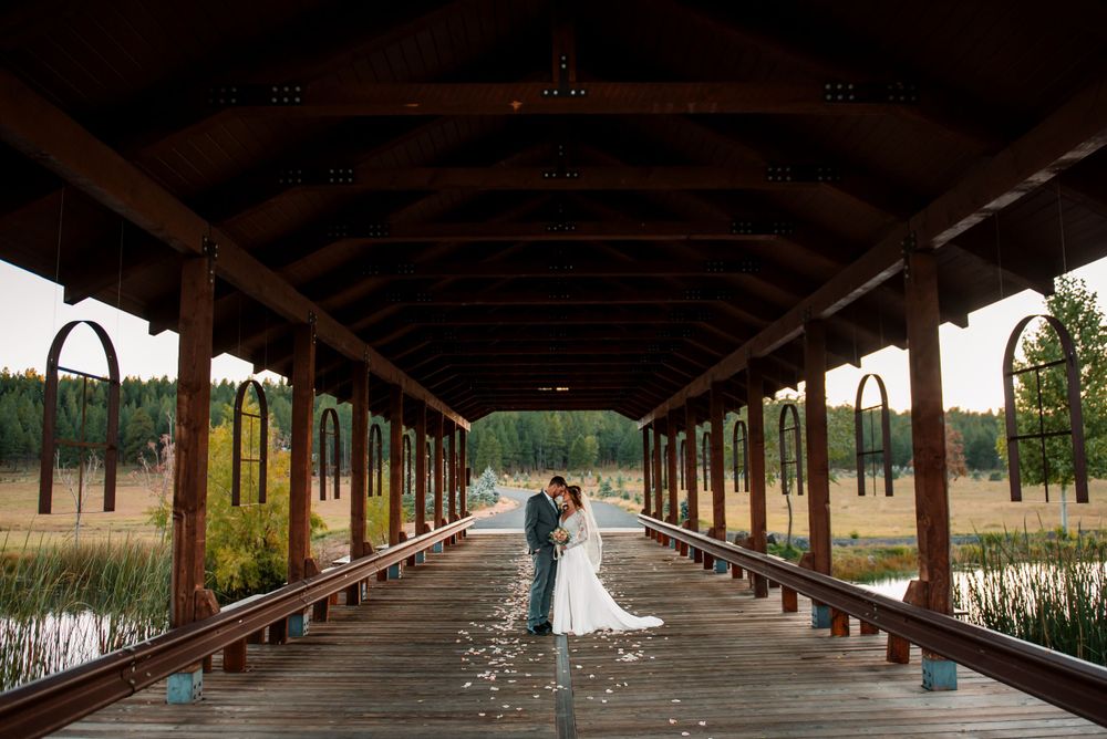 Long covered wooden walkway with rustic beams and natural lighting creates dramatic wedding venue.