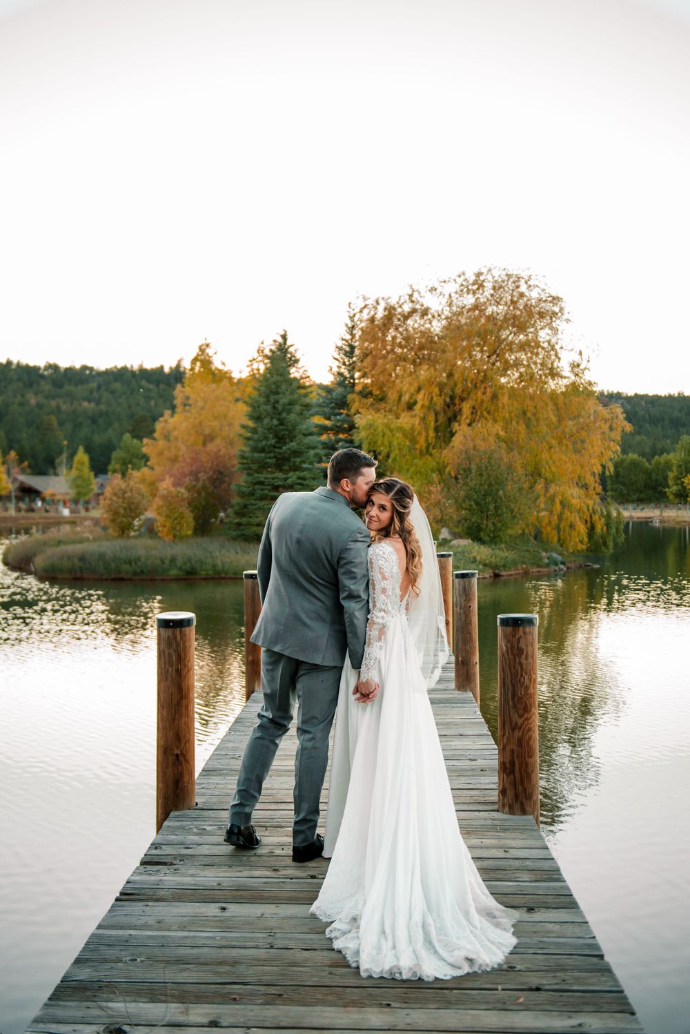 Romantic wedding photos captured on a wooden dock during golden hour by a serene lake.