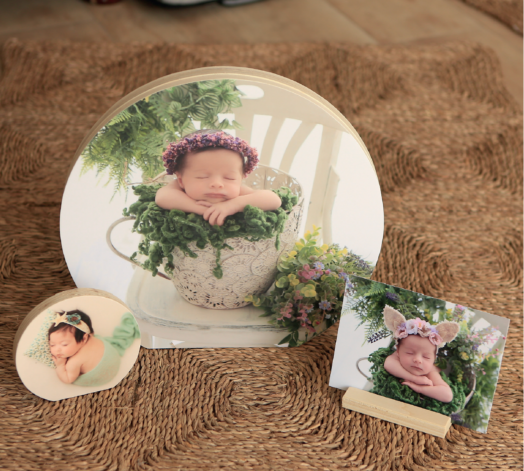 Newborn photography prints displayed on textured brown surface with floral decorations.