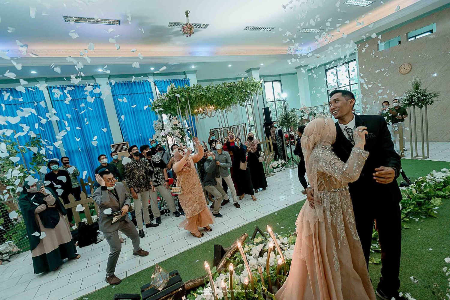 Wedding celebration with confetti and blue lighting in an elegantly decorated indoor venue.