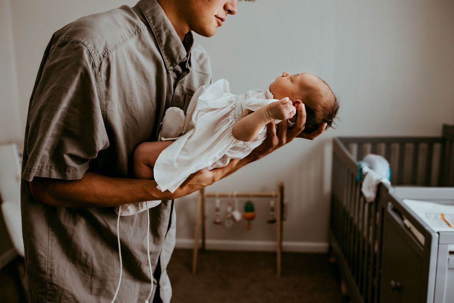 A tender moment of parent cradling a newborn baby in a nursery setting.