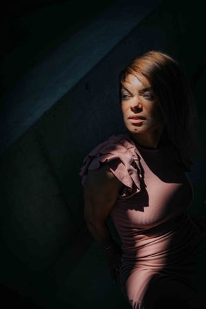 Dramatic low-key portrait in pink lighting with deep shadows.
