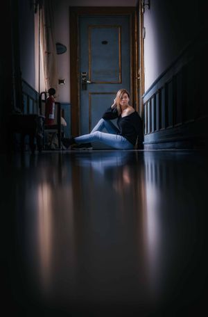 Dark hallway with dramatic lighting and reflective floor creating moody atmosphere.