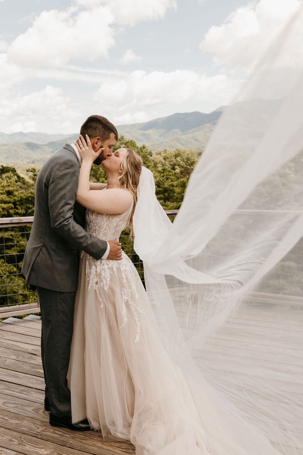 Wedding couple kissing on a deck with the bride's veil dramatically sweeping across the foreground.