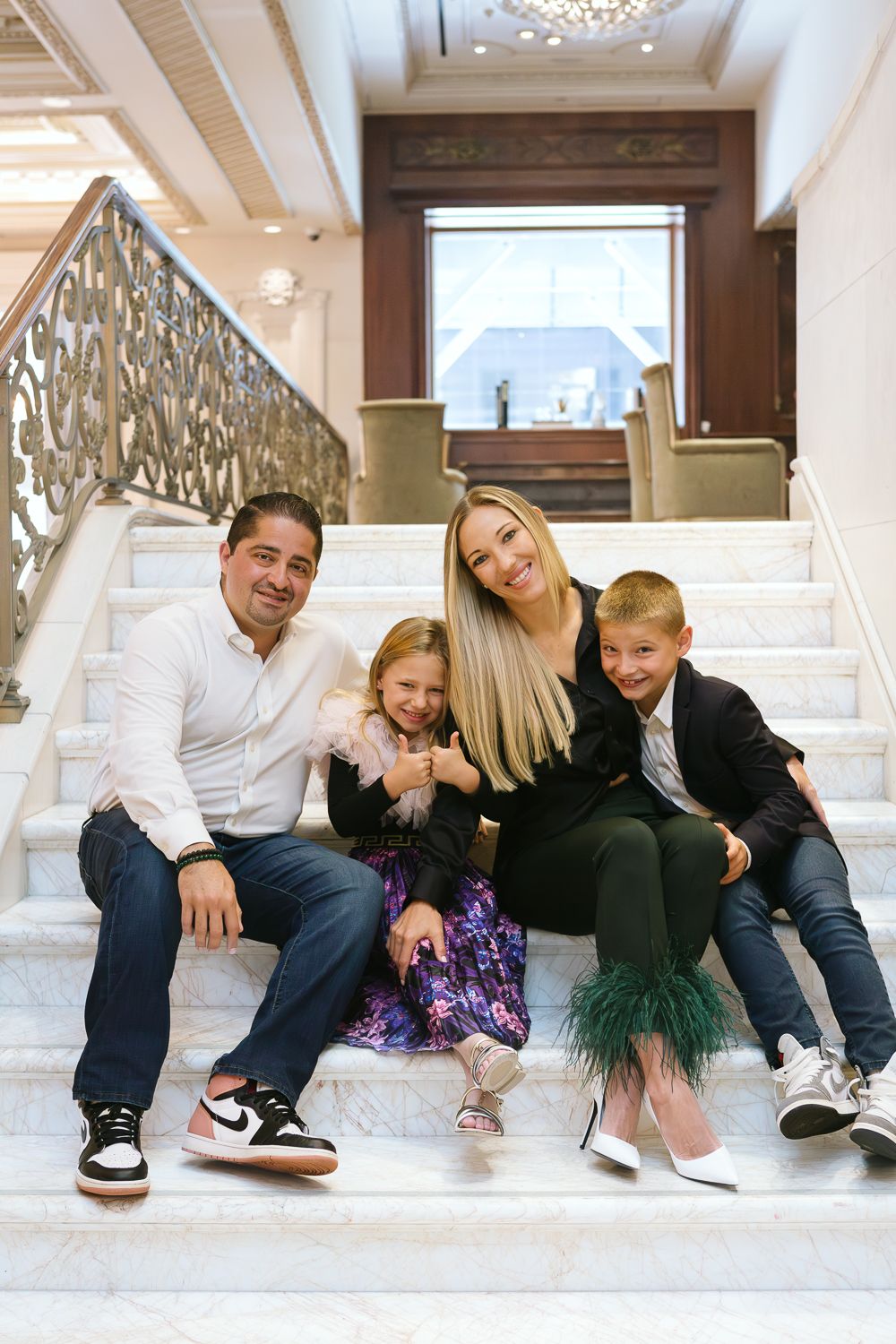 Family seated on the grand staircase of Plaza Hotel, NYC family photographer Paula Ortiz