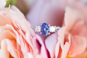 Stunning sapphire and diamond engagement ring nestled in soft pink rose petals.