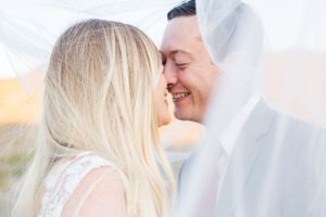 Intimate wedding portrait with couple sharing a tender moment under a veil.