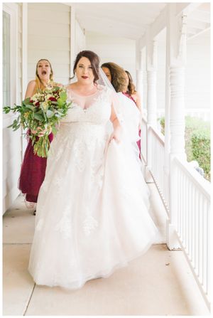 A beautiful wedding party on a white porch with bridesmaids in burgundy dresses.