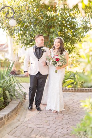 Couple shares joyful moment walking together on garden path under sunlit trees.