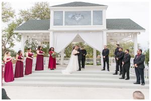 Wedding ceremony at an elegant white chapel with burgundy-dressed wedding party.