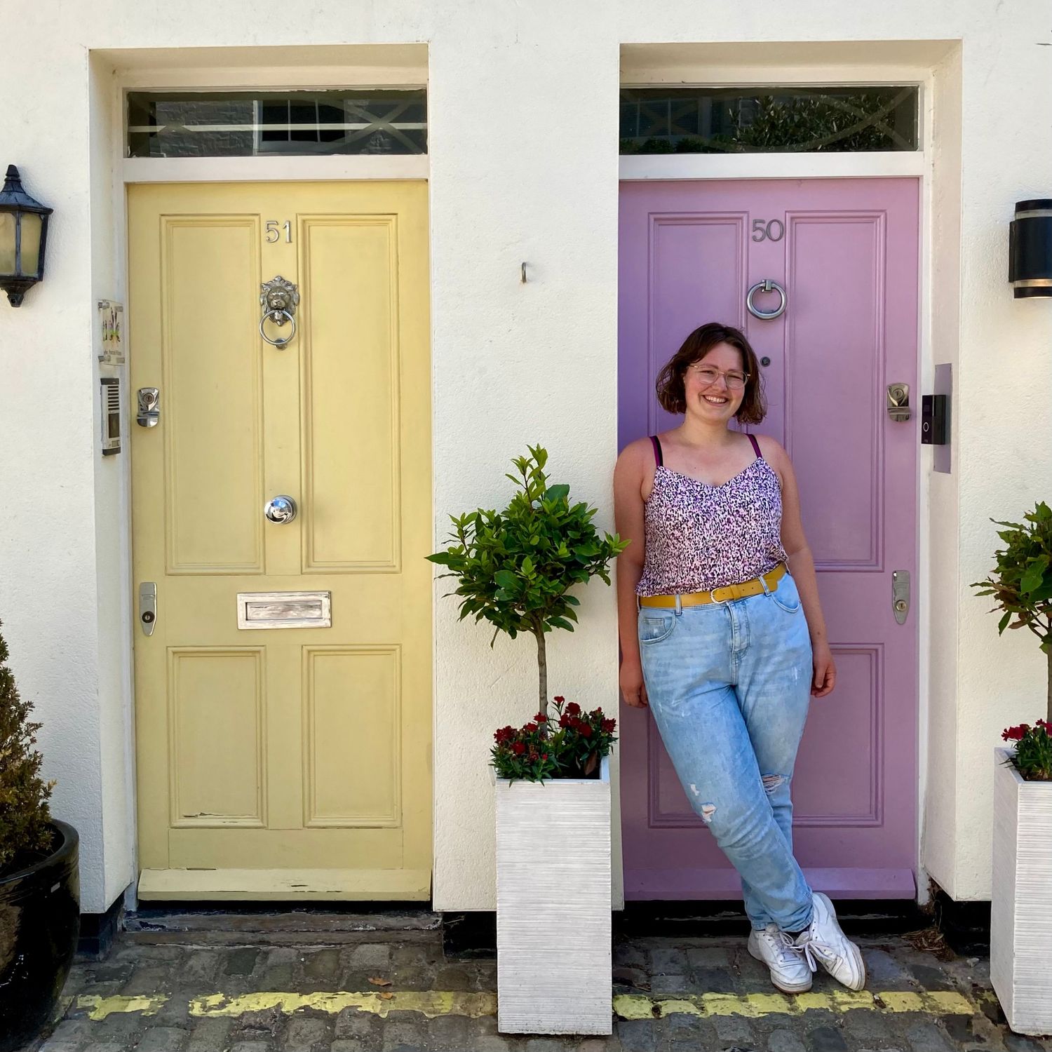 A picture of me in London. I'm smiling at the camera and my outfit colors match the pastel yellow and lilac doors.