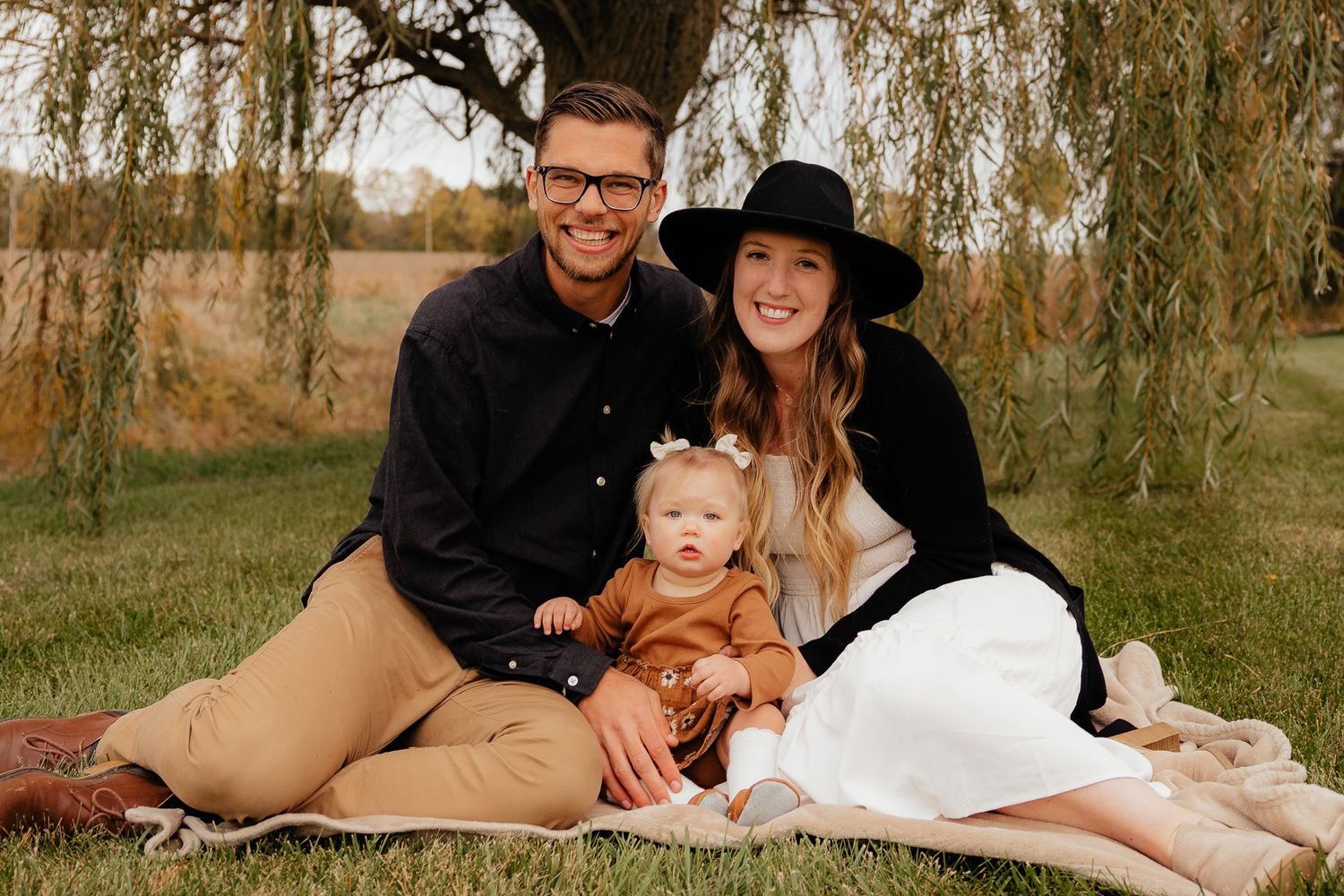 Family portrait session in a natural outdoor setting with willow trees in autumn.