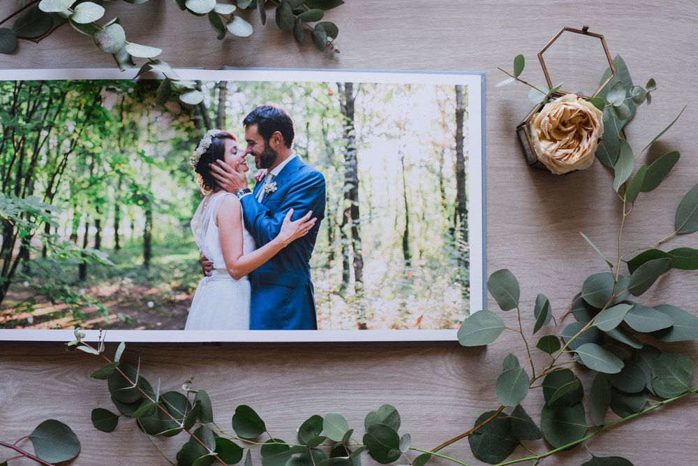 Wedding photograph displayed on wooden surface with eucalyptus leaves and dried flower decoration.