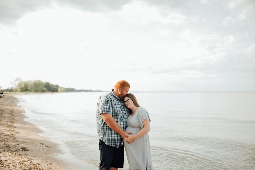A loving couple embraces during their beachside maternity photo session.