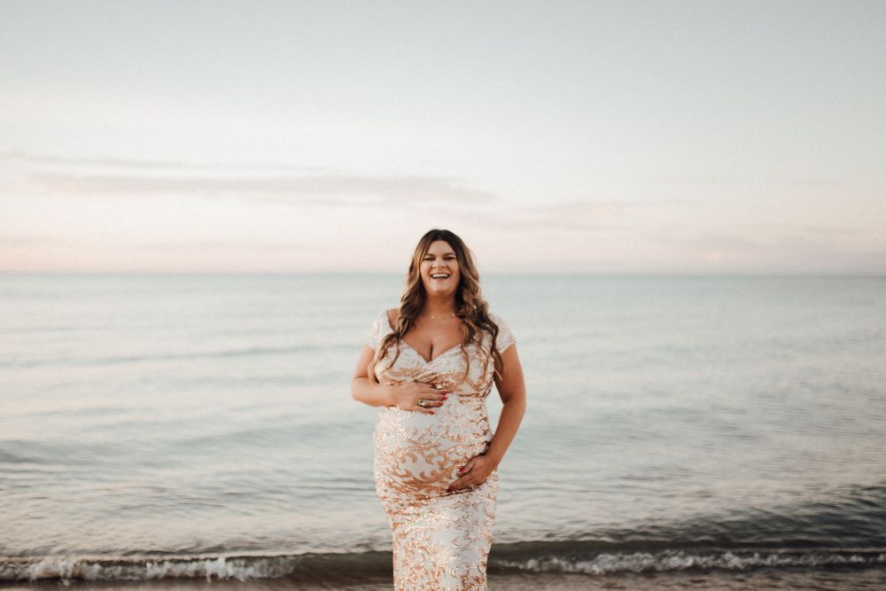 Maternity photo at beach during sunset showing silhouette against ocean horizon.