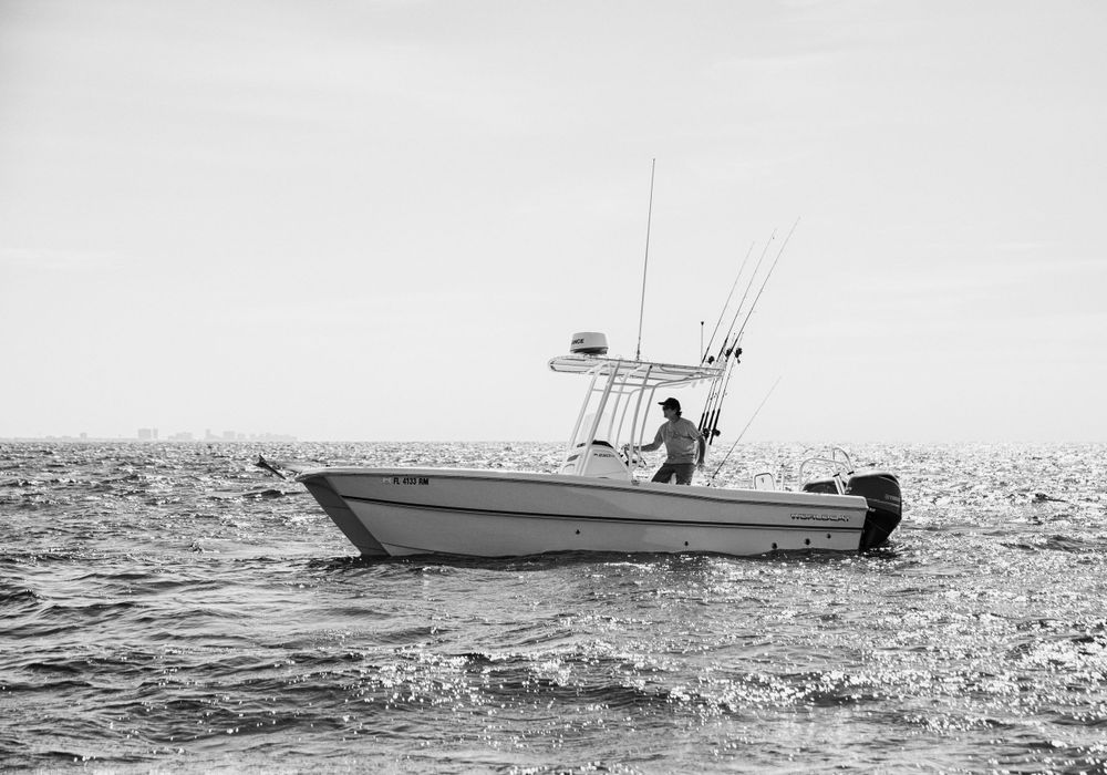 A fishing boat silhouetted against the horizon on calm Gulf waters.