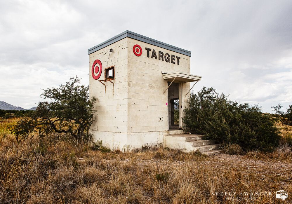 Abandoned Target store building in desert landscape under cloudy sky.