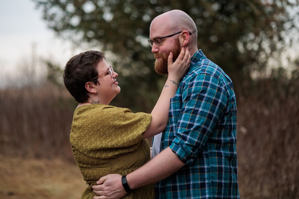 Intimate embrace between couple wearing blue plaid and mustard yellow outdoors.