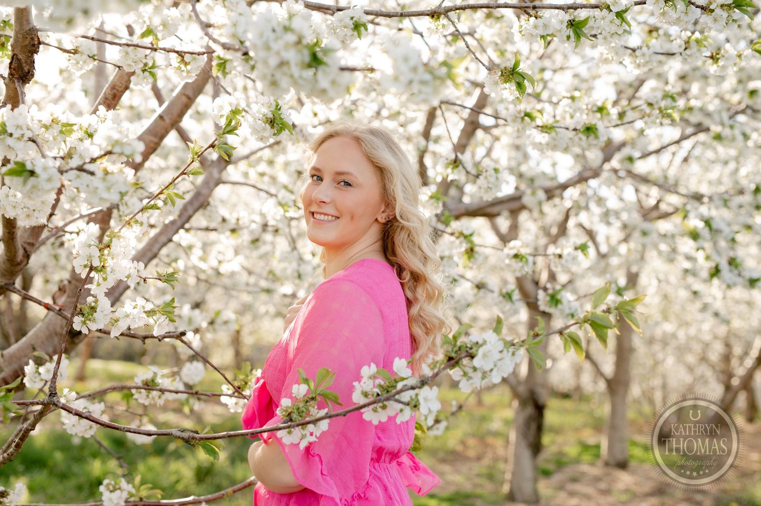 Natural light portrait amid blooming spring trees with soft white petals.