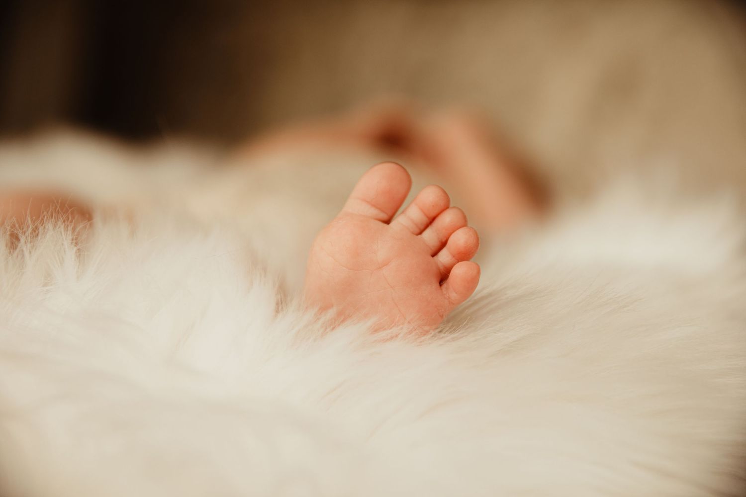 Newborn baby foot in white fur