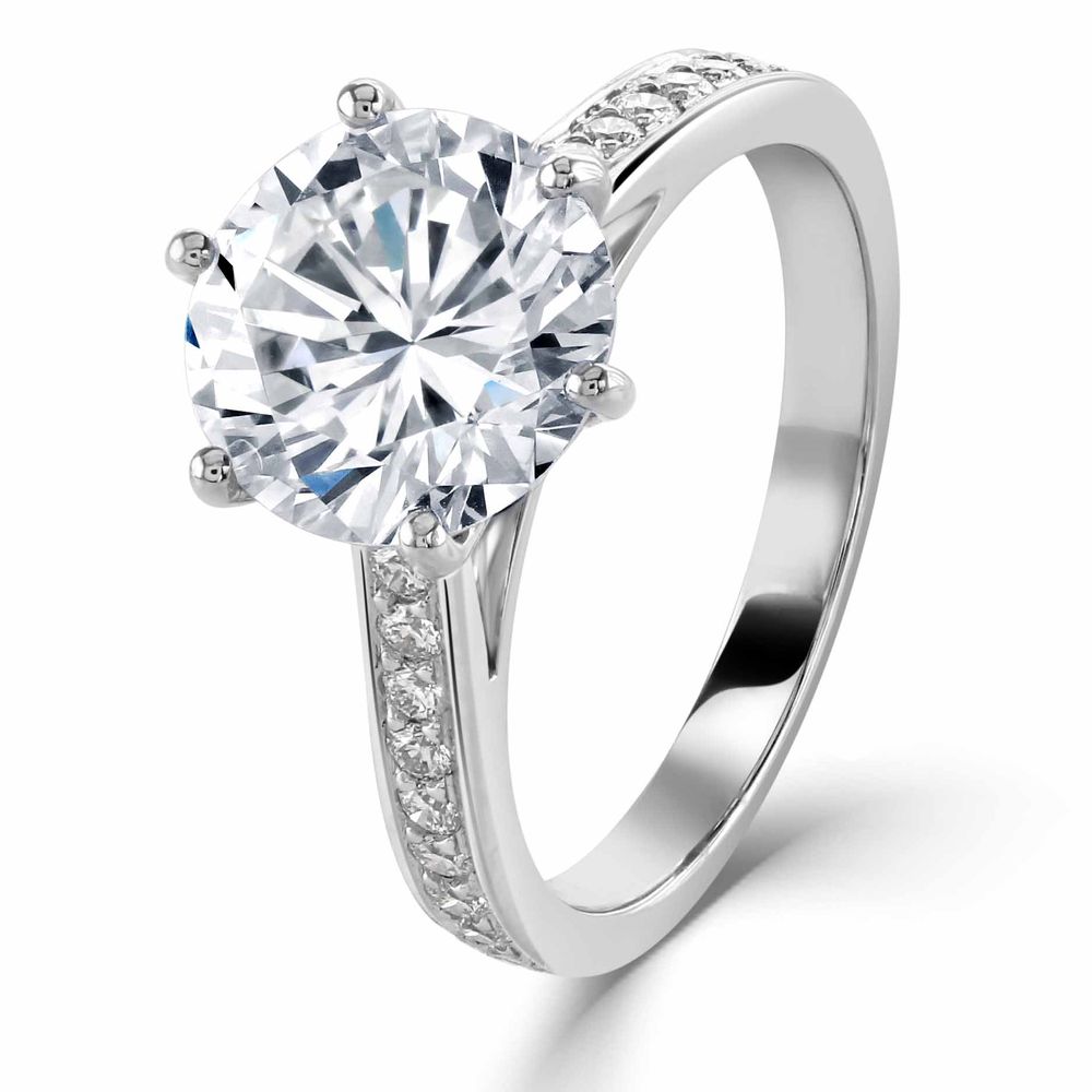 Classic solitaire engagement ring with large round diamond and pave band in white gold.