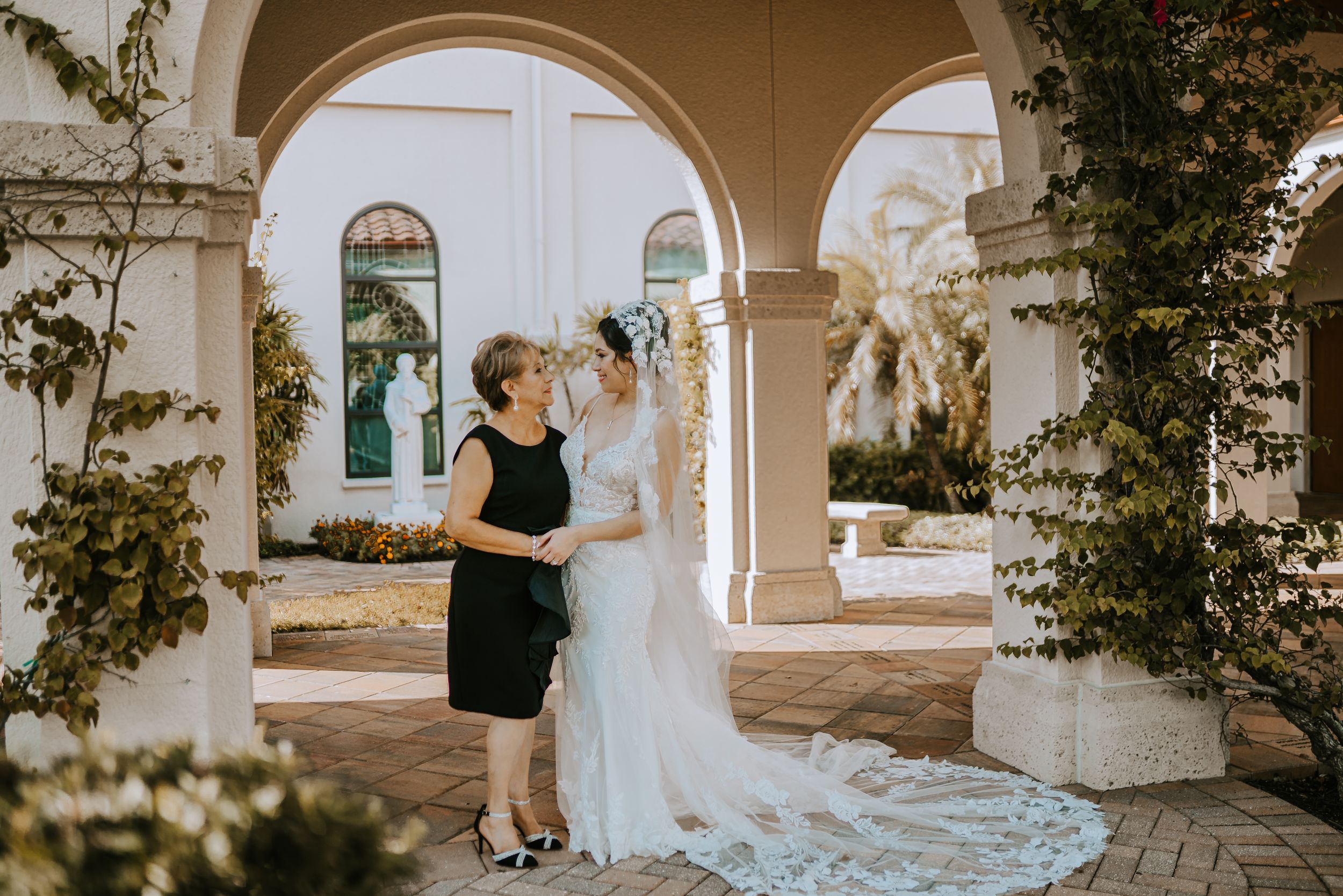 Elegant wedding scene under Mediterranean archways with flowing bridal gown and decorative vines.