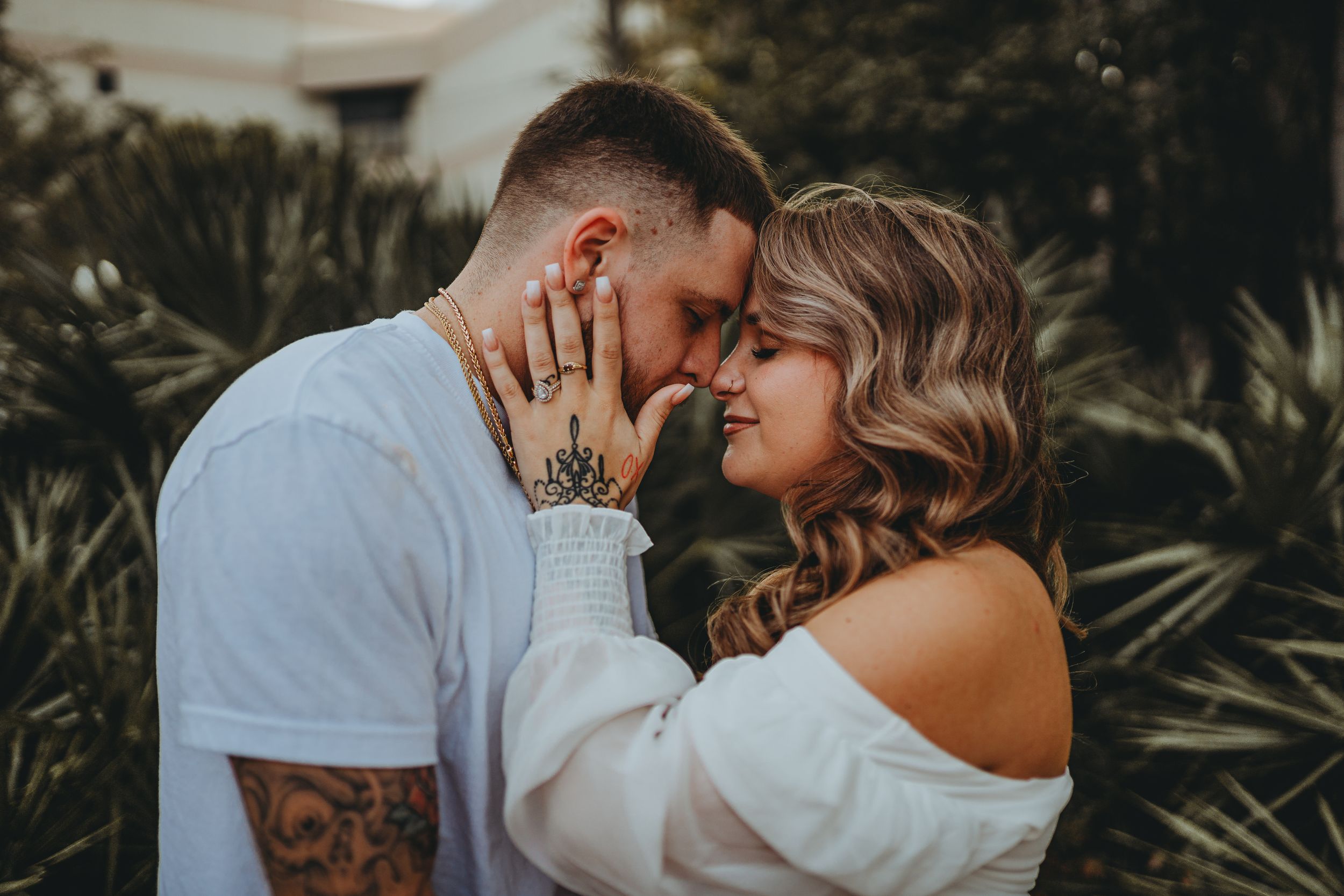 Romantic close-up portrait of couple against tropical foliage background.