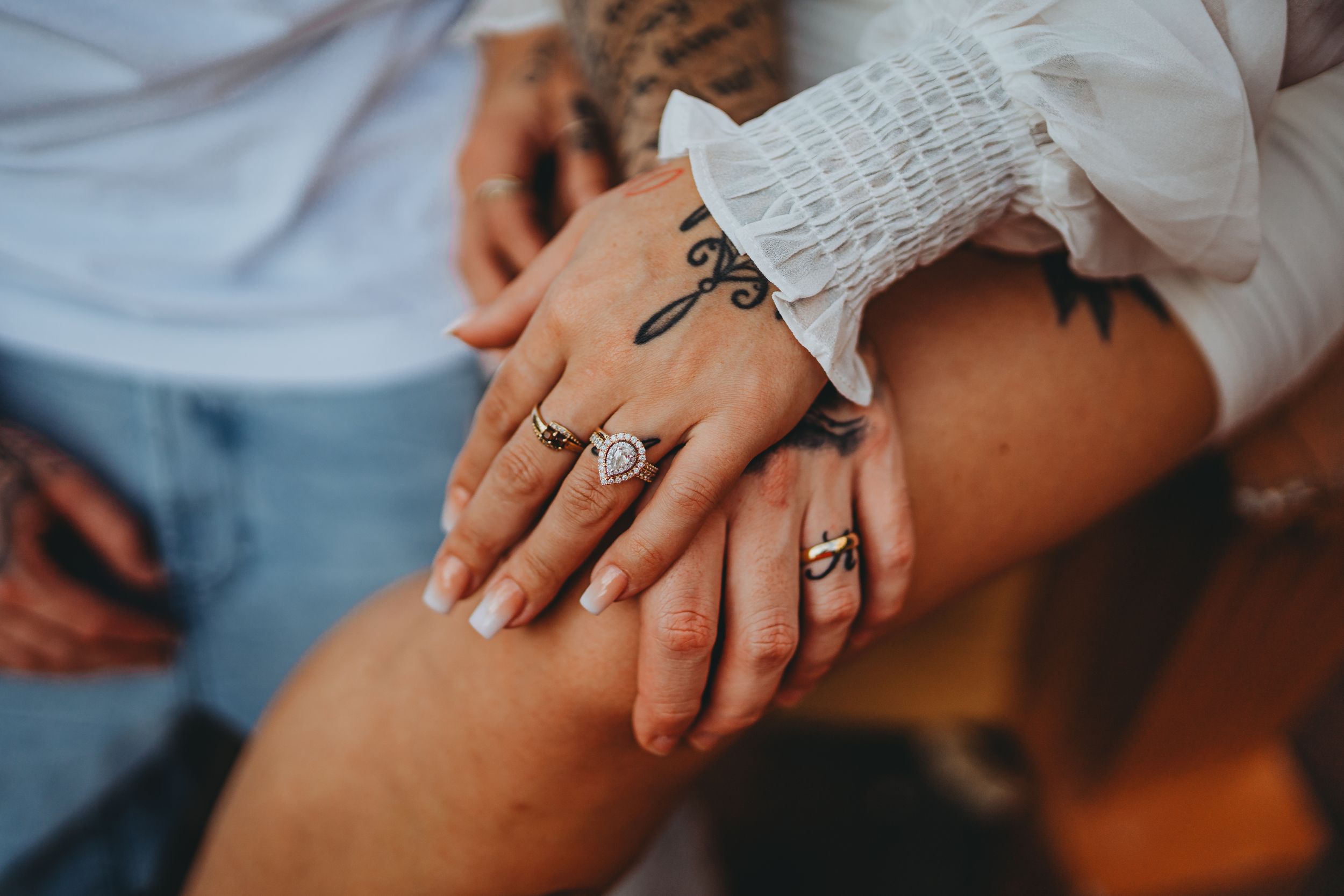 Close up of hands with engagement rings and white lace sleeve detail.