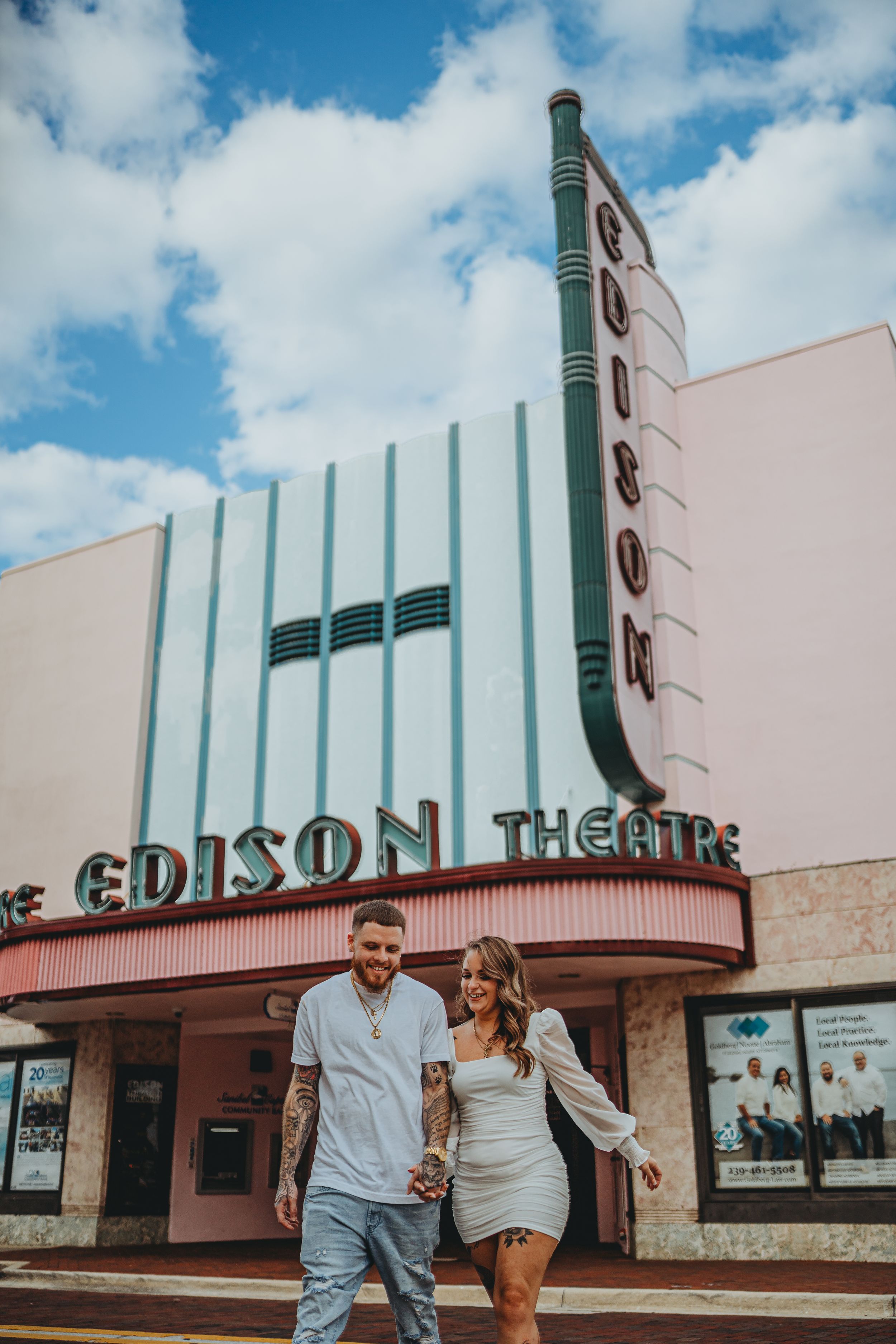A couple poses in front of the vintage Edison Theatre with its distinctive art deco signage and architecture.