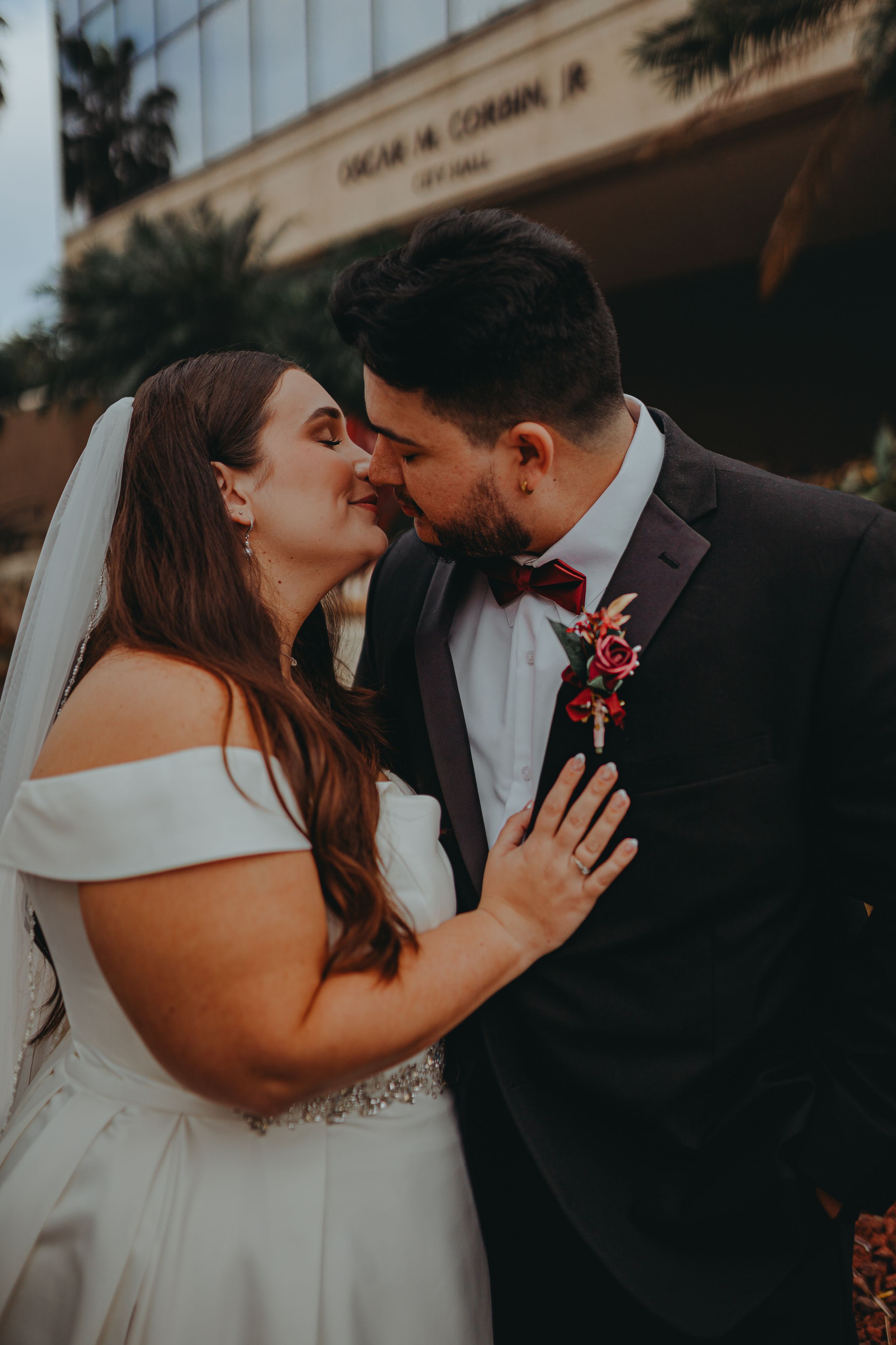 Romantic moment between bride in off-shoulder gown and groom in black tuxedo.