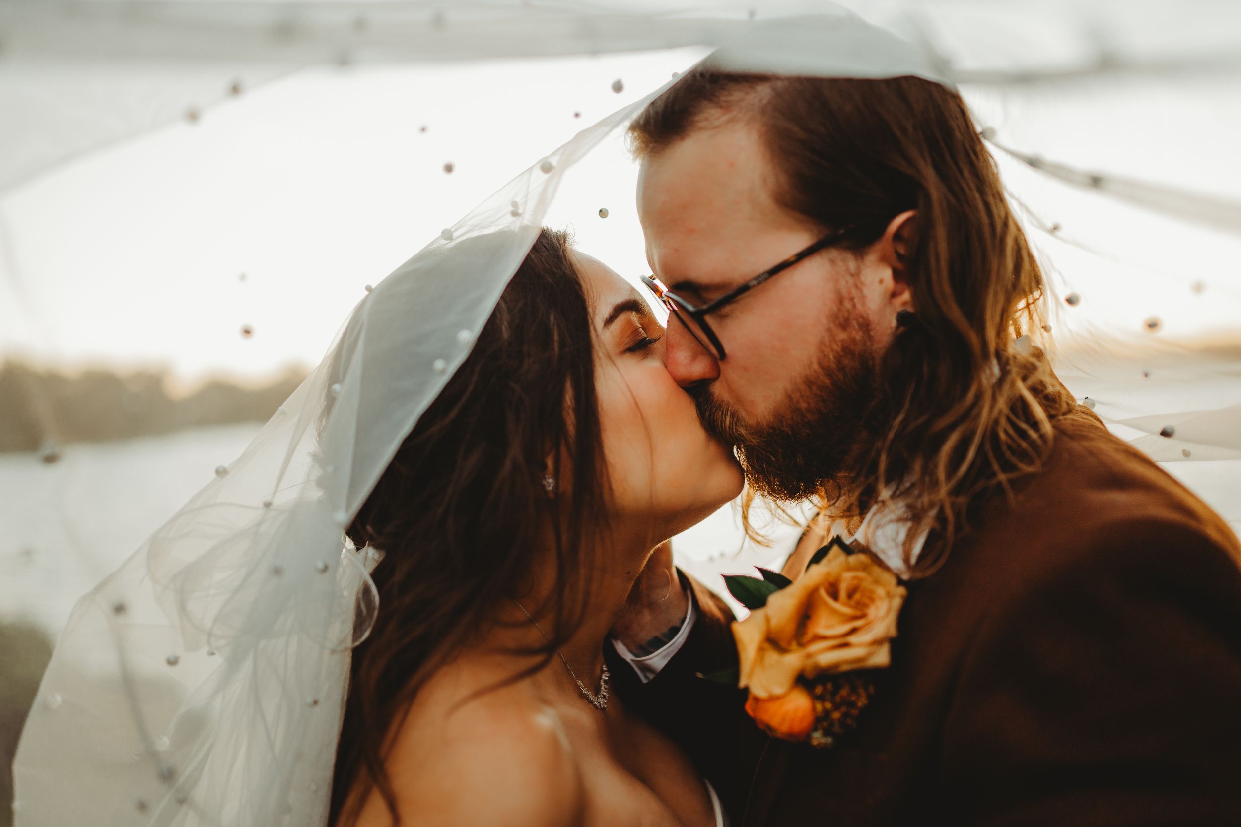 Romantic sunset moment with veil flowing in golden light.