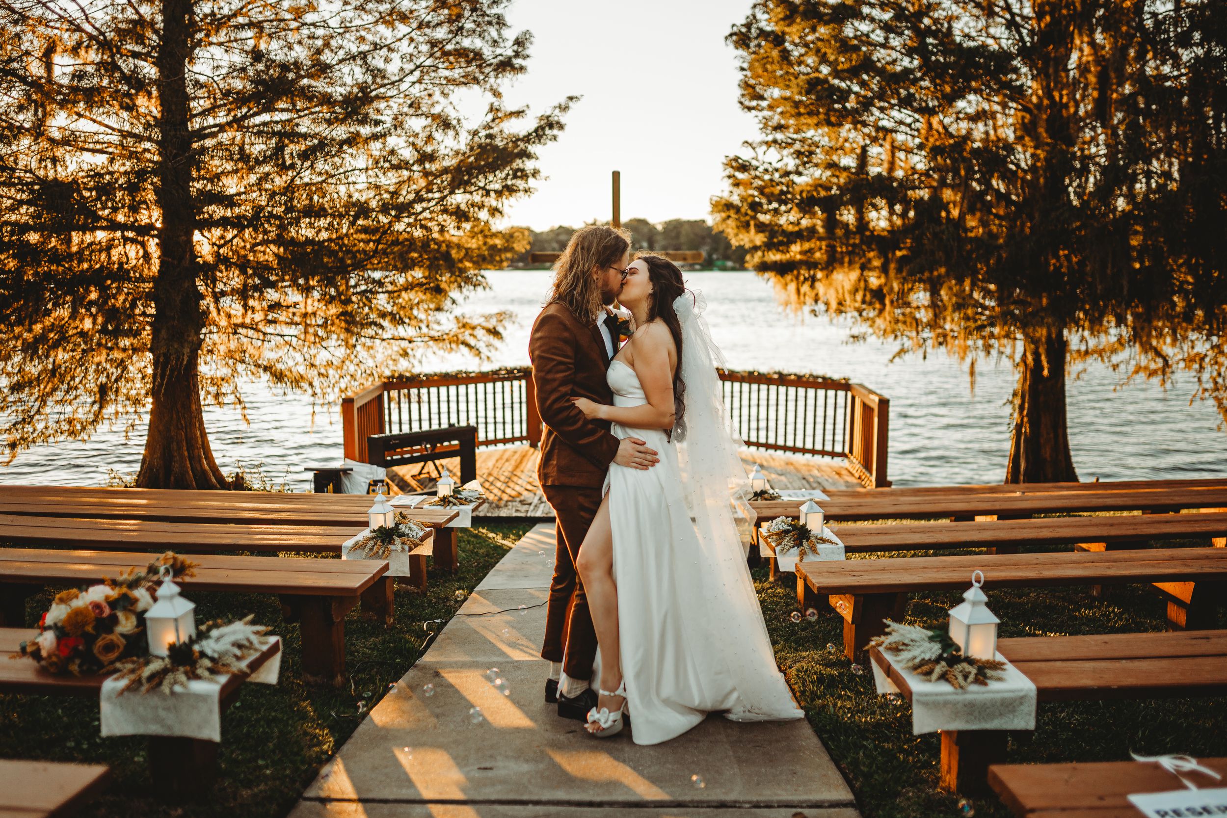 Waterfront wedding ceremony setup with wooden benches at golden hour.