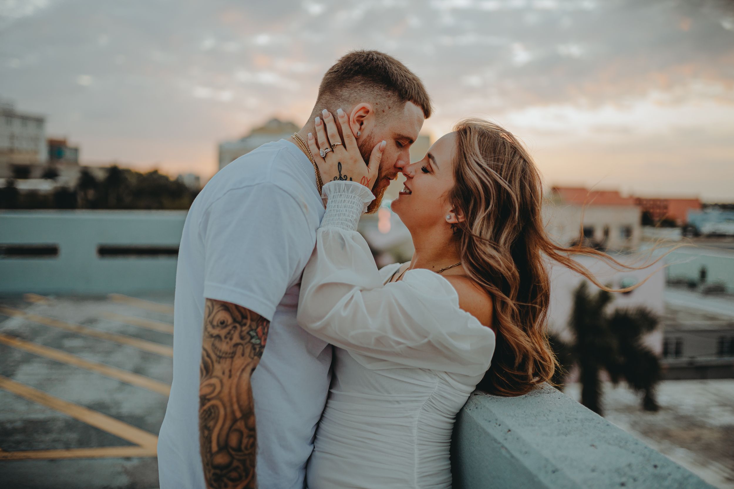 Intimate couple sharing tender moment on urban rooftop during golden hour photography session.