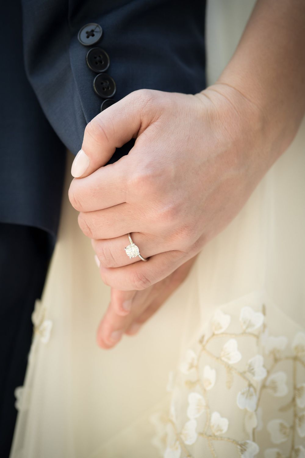 Close-up detail shots of hands wearing wedding rings against a white dress.
