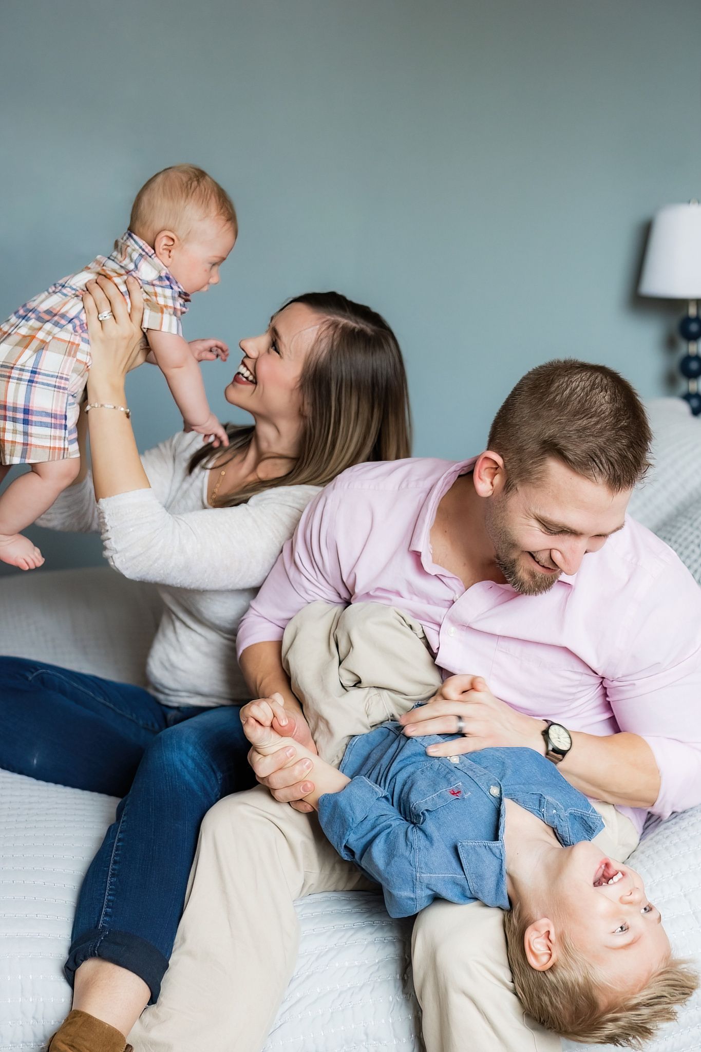 Family plays together on couch during casual lifestyle photo session.