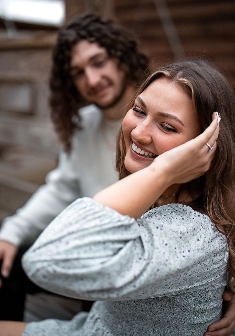 A woman in a sparkly sweater laughs joyfully while posing against a dark background.
