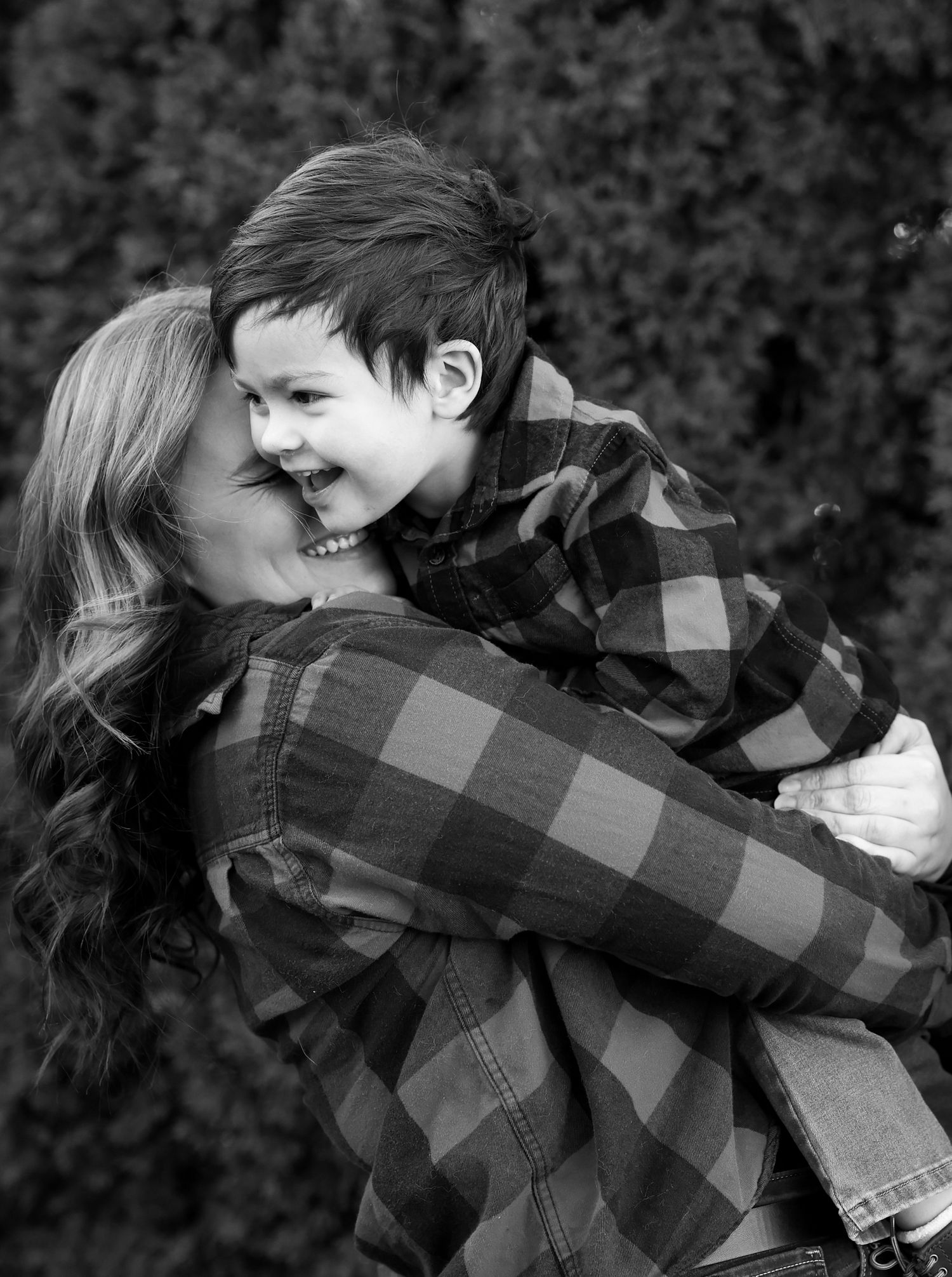 A joyful embrace between two people wearing matching plaid flannel shirts captured in black and white.