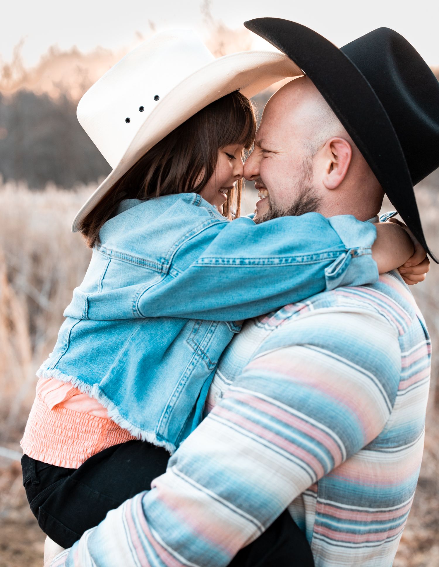 Couple in western attire embraces during sunset photo session.