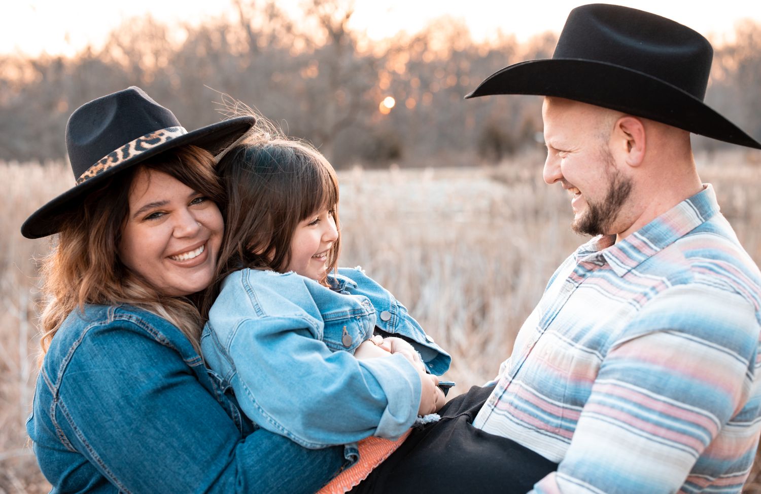 Family wearing western hats shares candid moments during sunset photo session.