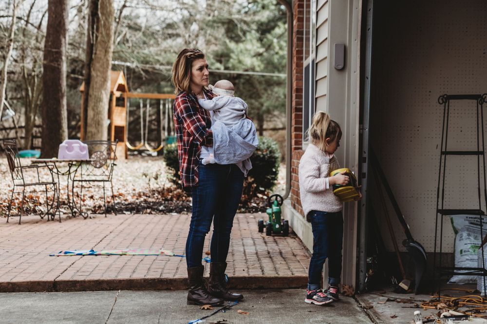 Family gathering on brick patio near play structure and house exterior.