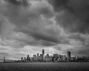 Dramatic stormy sky over San Francisco skyline with Bay Bridge in black and white.